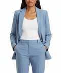 Woman wearing a light blue suit with a white top on a white background