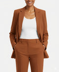 Brown suit jacket and pants with a white top on a light gray background