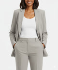 Woman wearing a gray suit with a white top on a light gray background